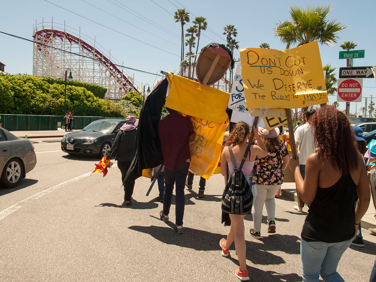 Supporters of the Beach Flats Community Garden march on Beach Street in Santa Cruz in front of the Giant Dipper rollercoaster at the Beach Boardwalk as part of a campaign to save the garden.